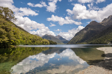 Fototapeta premium A man fishing from the banks of the calm waters of Lake Gunn in the South Island of New Zealand with David Peaks in the distance