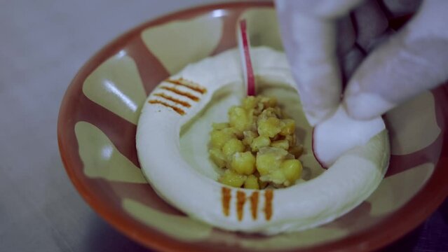 Decorating Fresh Hummus Dish With Radish All Around And Cumin