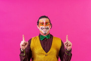 Clown with white face makeup showing empty space on pink background, announcing something, pointing...
