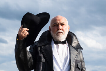 Fashion man in leather coat. Cool gray bearded male confidently posing. Gangster style. Older...