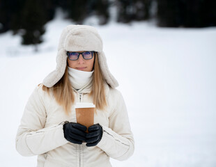 girl in winter in light clothing holding a brown drink glass (coffee, tea) suitable for mocup