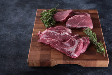 Fresh raw meat.Beef tenderloin. Two types of beef tenderloin on a wooden board. Juicy pieces of meat. Rosemary branch.