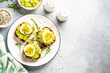 Avocado sandwich. Whole grain bread with avocado and boiled eggs with arugula. Top view on white background.