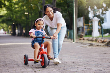 Mother, kid and bicycle teaching with training wheels for learning, practice or safety at the park....