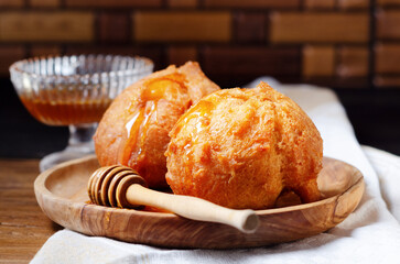 Close-up of italian Carnival fritters with honey- Strufoli di Carnevale  sweet dish typical of Umbria for Carnival, on a wooden plate on a rustic background.