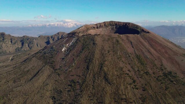 Aerial view orbiting Mount Vesuvius peak, South Italy under sunny blue sky
