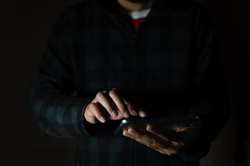 Cheerful bearded man in black long sleeve shirt using digital tablet in Dark room. hand holding tablet. 