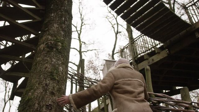 Female looking up at treehouse in forest.