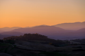 Sunrise in the typical Tuscan hills with cypresses, vineyards and house, Tuscany, Volterra, Italy