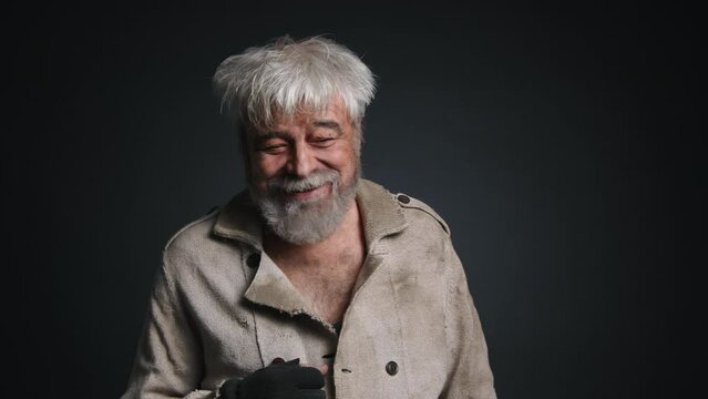 Portrait of a homeless, caucasian man looking carefree and cheerful. Close-up view of adult, gray-haired male smiling and dancing. High quality 4k footage