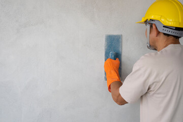 A man wear hard hat and gloves holding trowel plastering cement wall, concept for industrial work,...