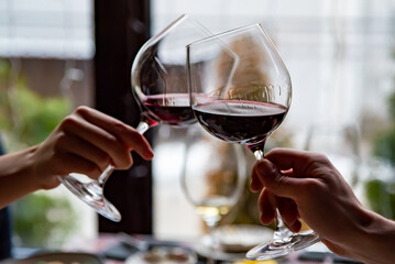 Close up of hands young couple toasting with glasses of red wine at restaurant