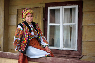 Ukrainian girl in national Hutsul clothes sits on the porch of his house