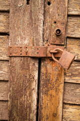 Extremely rusty lock on an old and weathered wooden door