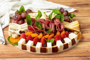 Antipasto catering platter with salami and cheese on a wooden background. Side view with close up