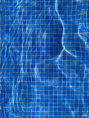 Background of blue mosaic tiles seen through water in a swimming pool