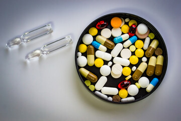 multicolored vitamin pills and vaccine ampoules close-up