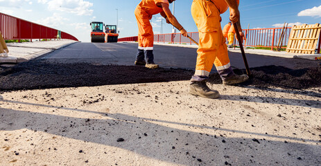 Workers are using shovels for realign hot asphalt to correct measure
