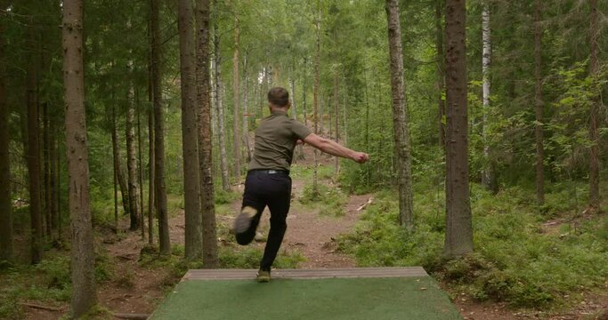 Disc golfer throws a backhand opening throw from the tee