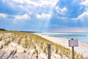 Sun rays shining through thick clouds on the beach of the Baltic Sea.Sign beach crossing