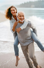 Dynamic couple of seniors running on a beach. They look at the camera. Generative AI