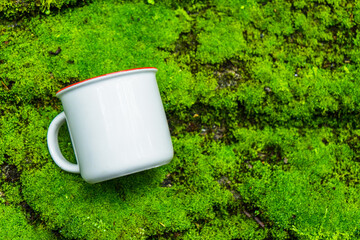 Obraz premium An enamel mug laying out on the top of calming looking green moss