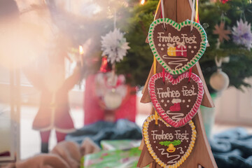Christmas food. Colorful Christmas handmade gingerbread in the shape of heart hangs on wooden tree close-up. Behind Santa. Bokeh effect. Selective focus