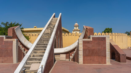 A sundial in the ancient famous observatory of Jantar Mantar. Divisions are applied on the curved white marble surface to determine the exact time. Stairs in the center. Blue sky. India Jaipur