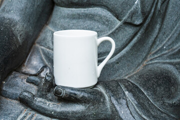 A gray statue holding up a coffee mug for mockup template