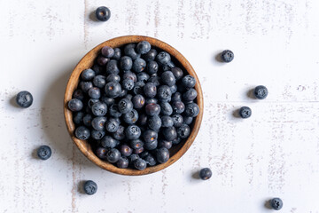 Top down view of a wooden bowl of fresh blueberries on white background