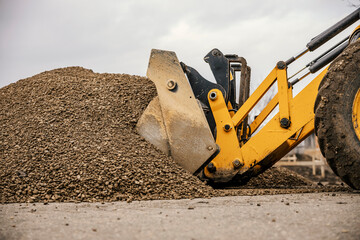 Cropped picture of a bulldozer working with gravel on construction site. - obrazy, fototapety, plakaty