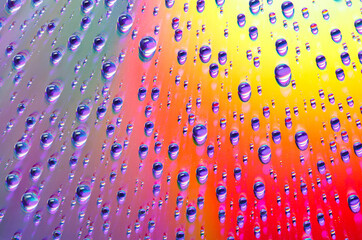 Water drops of different sizes close-up macro on multicolored abstract background