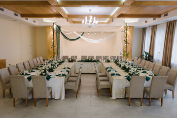 Wedding arch is decorated with textile fabric and garlands with light bulbs in restaurant. Festive dinner table, reception. Flower composition and candles. Setup. Setting in banquet area in hall.