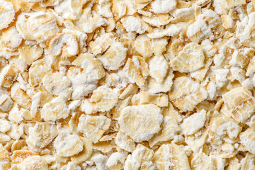 Oat flakes raw, bunch in bulk, close-up macro view, background wallpaper, uniform texture pattern