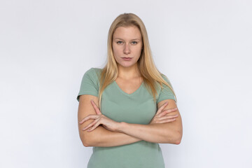 Fototapeta premium Disappointed woman looking at camera. Young female model crossing arms with serious face. Portrait, studio shot, disappointment concept