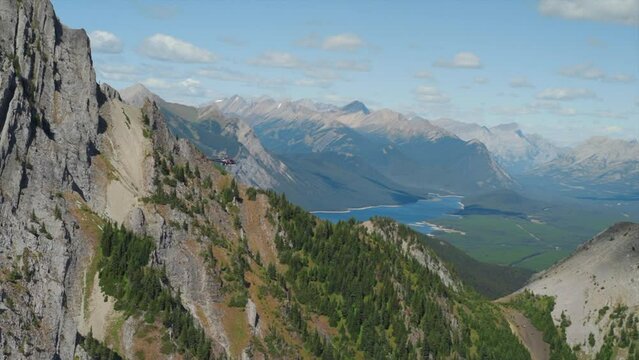 A thrilling helicopter tour of the Canadian Rocky Mountains, breathtaking aerial views of snow-capped peaks, glaciers, rivers, and forests. Wilderness from a bird's-eye view visible from above.