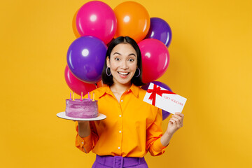 Happy fun young woman wears casual clothes celebrating near balloons hold cake gift certificate coupon voucher card for store isolated on plain yellow background. Birthday 8 14 holiday party concept.