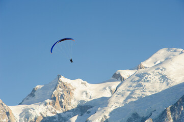 Naklejka na ściany i meble Paragliding over snow covered mountains