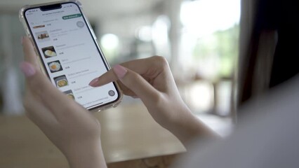 Orders food using online delivery, Young girl in with mobile phone in hands chooses fast food in an online store to place an orders in a restaurant