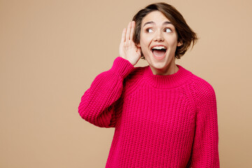 Young smiling curious nosy fun caucasian woman wear pink sweater try to hear you overhear listening...