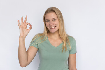 Fototapeta na wymiar Happy woman showing ok gesture. Young female model making ok sign. Portrait, studio shot, quality, support concept