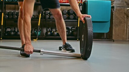 Closeup view of the naked torso man putting weight plates while preparing doing barbell workout