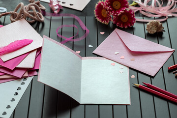 Schreibplatz mit Briefpapier und rosa Herzen auf dunklem Holz