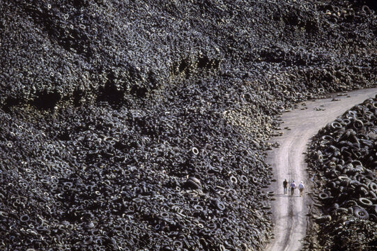 Three men walk through a mountain of tires, California, USA.