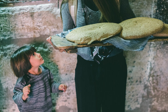 Kid staring at mother while she holds two traditional breads, Medina, Marrakesh, Morocco