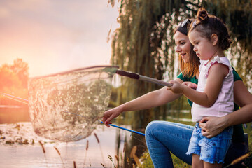 Fishing with mom. Mother and daughter fishing together on the river.  Side view. Selective focus.