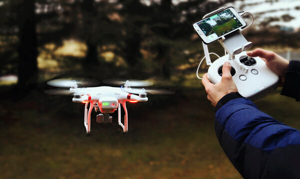 Hovering drone and hands of person holding remote