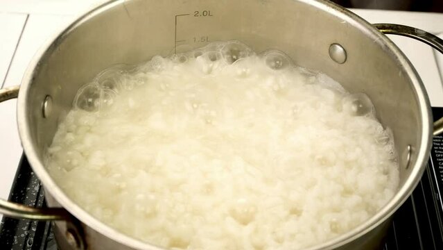 Boiling round rice in metal pot prepare.