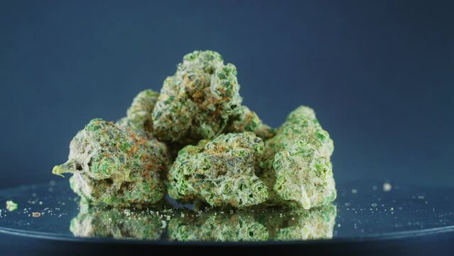 Grayish Green Dried Marijuana Buds - Close Up concept Shot, pile of dried marijuana plants, orange trichomes strains, on a reflecting rotating stand, studio lights, slow motion, 4K video