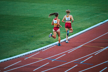 Group of determined female athletes pushing through the 5000m race on track, showcasing their athleticism, focus and physical fitness